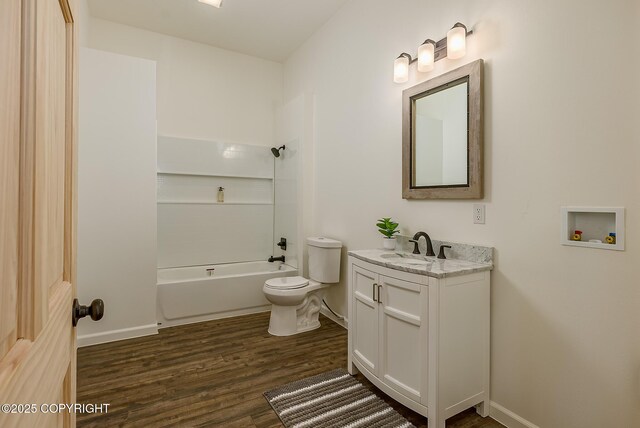 full bath with toilet, wood finished floors, vanity, baseboards, and tub / shower combination