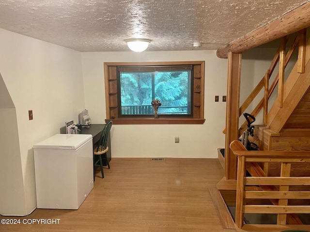 clothes washing area with light wood-type flooring, visible vents, and a textured ceiling