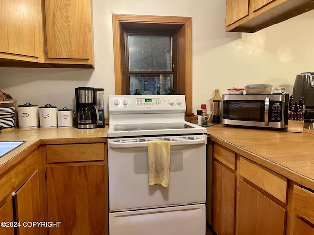 kitchen featuring brown cabinetry, light countertops, stainless steel microwave, and electric range