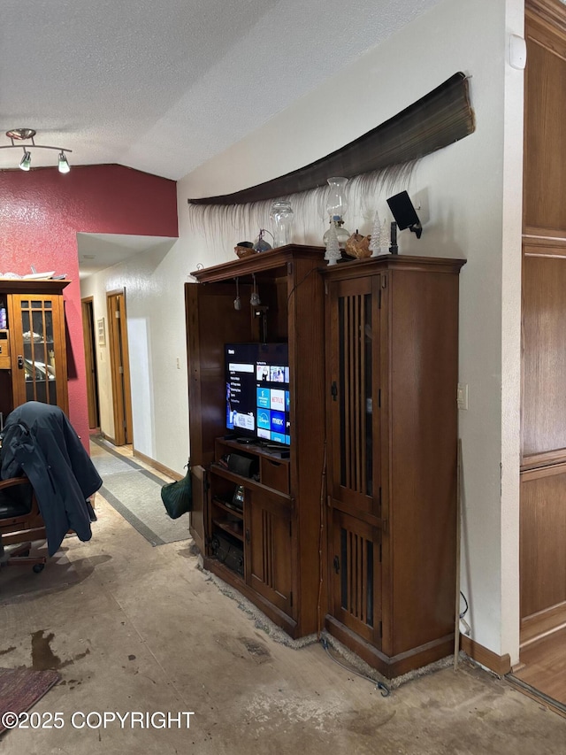 unfurnished living room featuring vaulted ceiling, concrete flooring, baseboards, and a textured ceiling