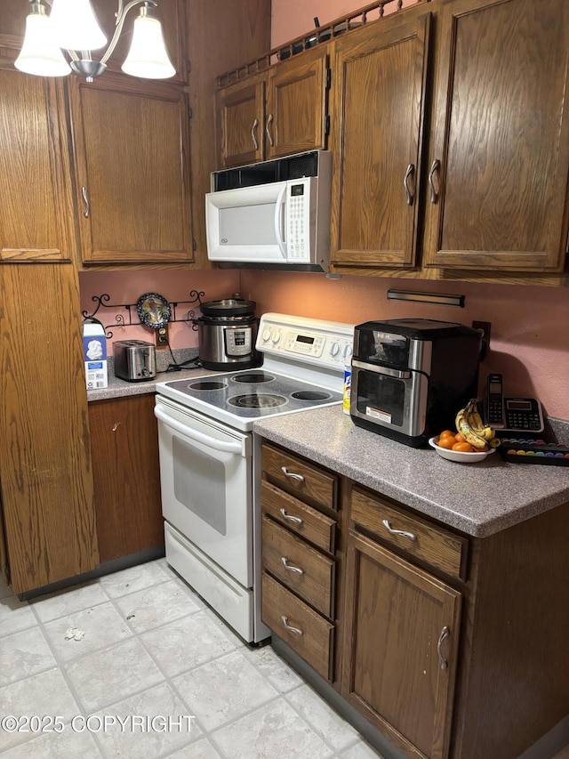 kitchen with white appliances, brown cabinetry, and decorative light fixtures
