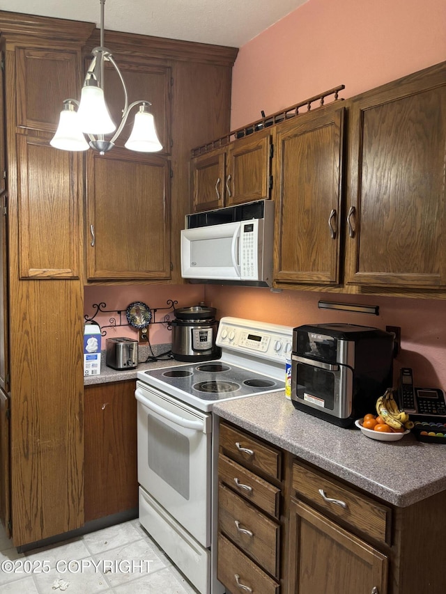 kitchen featuring white appliances, hanging light fixtures, light tile patterned flooring, and brown cabinets