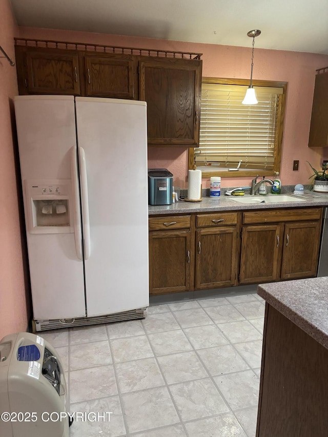 kitchen with white fridge with ice dispenser, a sink, decorative light fixtures, and light countertops