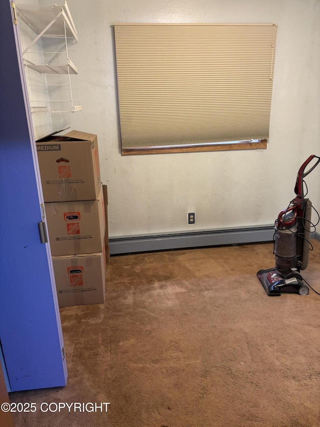 spare room featuring a baseboard heating unit and carpet flooring