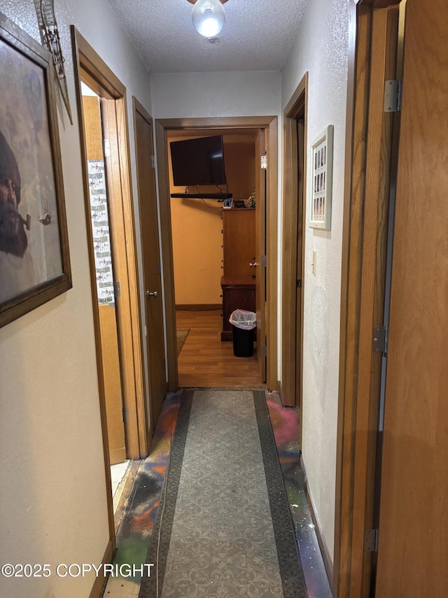 hallway featuring a textured ceiling and a textured wall