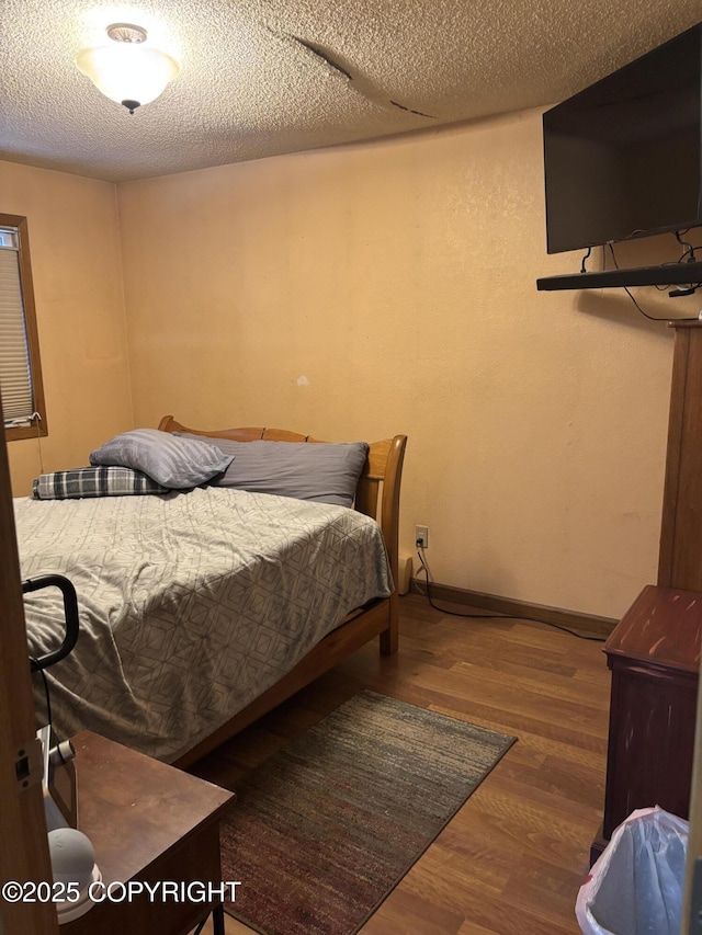 bedroom with wood finished floors, baseboards, and a textured ceiling