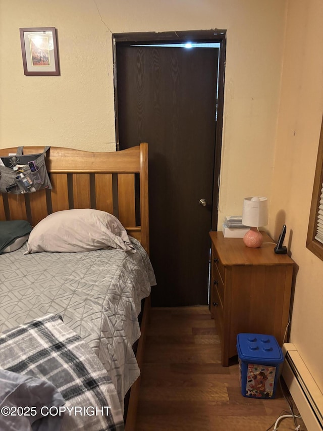 bedroom with baseboard heating and wood finished floors