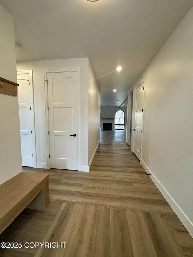 corridor with baseboards, wood finished floors, and recessed lighting