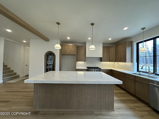 kitchen with backsplash, stainless steel dishwasher, a sink, a center island, and range