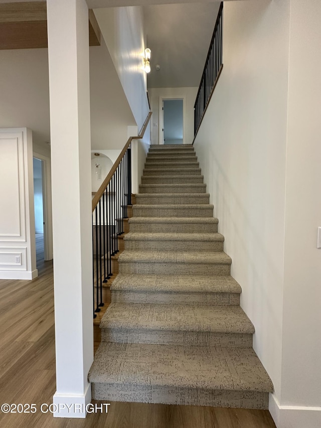 staircase featuring wood finished floors and baseboards