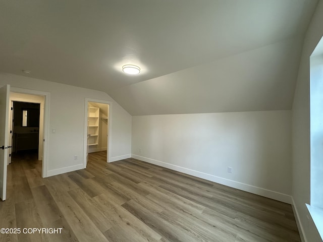 additional living space with wood finished floors, baseboards, and vaulted ceiling