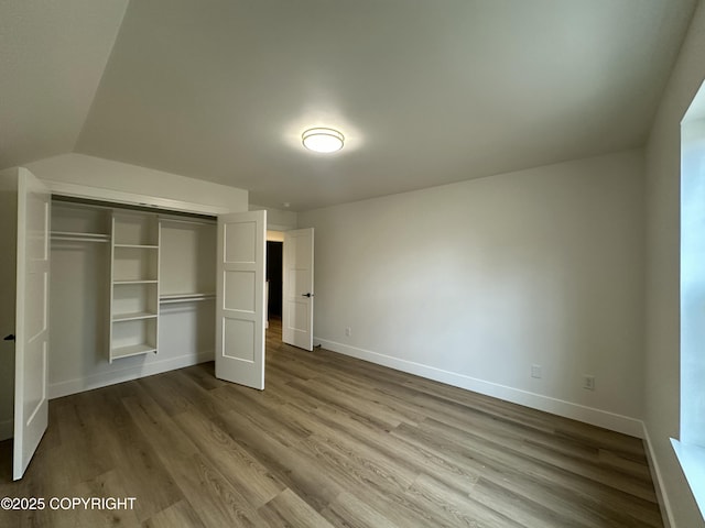 unfurnished bedroom with baseboards, wood finished floors, and a closet