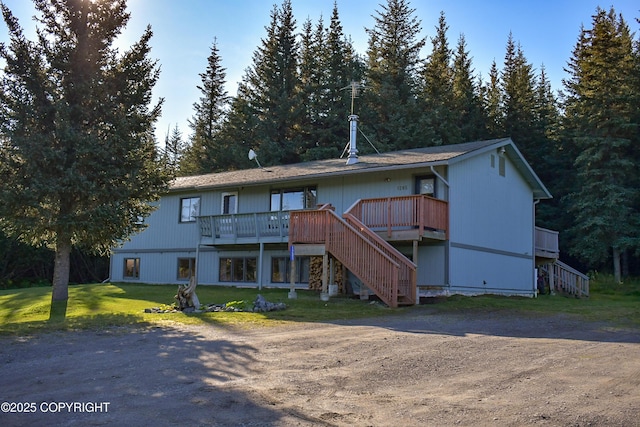 rear view of house featuring a deck, a yard, and stairway