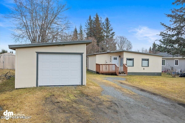 view of front facade featuring dirt driveway, a front lawn, an outdoor structure, and a wooden deck