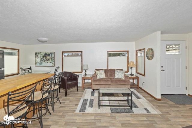 living room featuring a textured ceiling, plenty of natural light, and light wood-style flooring