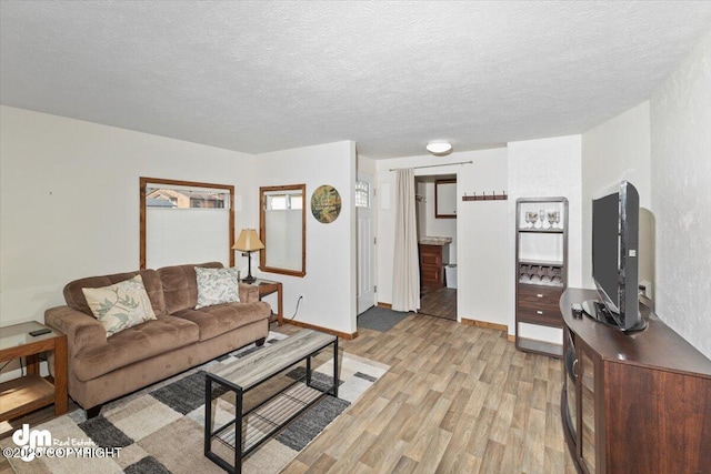 living area with light wood-style floors, baseboards, and a textured ceiling