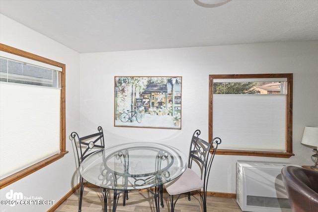 dining area with light wood-type flooring, heating unit, and baseboards