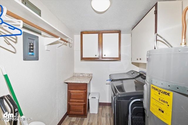 laundry room with cabinet space, electric water heater, a textured ceiling, separate washer and dryer, and wood finished floors