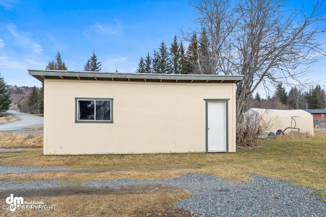 view of side of home with an outbuilding and stucco siding