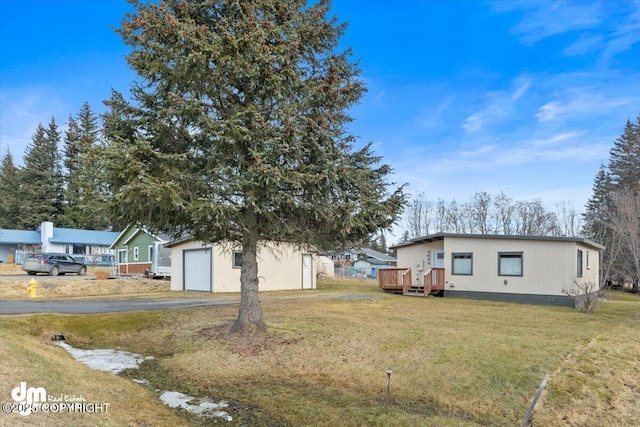 view of front of home with an outbuilding, a deck, aphalt driveway, a garage, and a front lawn