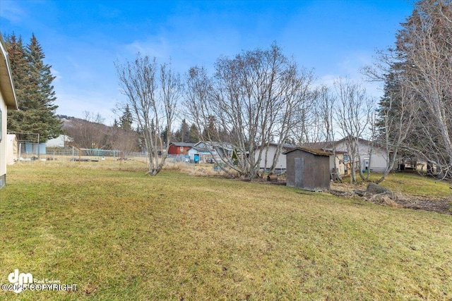 view of yard with a storage shed, an outdoor structure, and fence