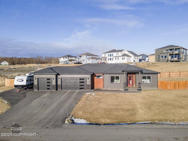 prairie-style house with a garage, a residential view, fence, and aphalt driveway