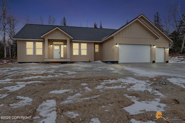 view of front of property featuring a garage, driveway, and a shingled roof