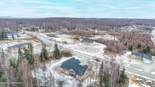 snowy aerial view with a wooded view