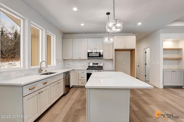 kitchen with appliances with stainless steel finishes, a sink, light wood-style floors, and a center island