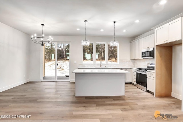 kitchen with a center island, light countertops, light wood-type flooring, decorative backsplash, and stainless steel range with gas stovetop