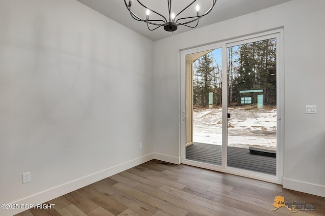 entryway featuring baseboards, wood finished floors, and an inviting chandelier