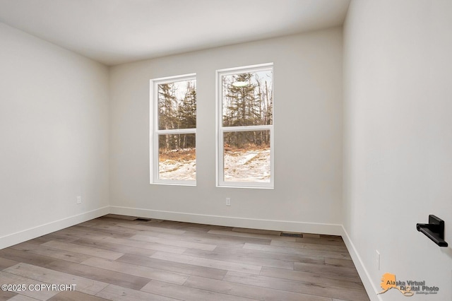 empty room featuring visible vents, baseboards, and wood finished floors