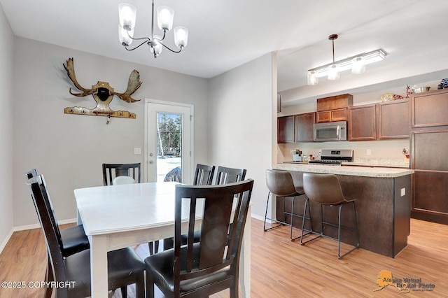 dining room featuring baseboards, an inviting chandelier, and light wood-style floors