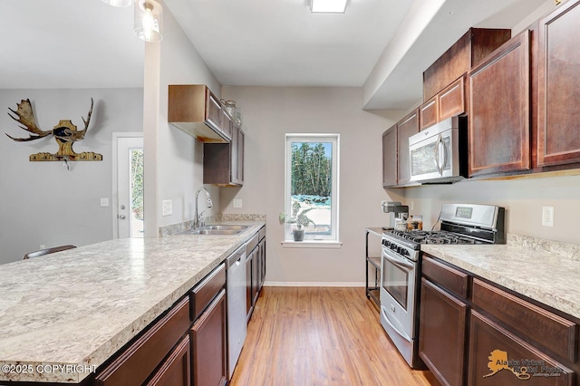 kitchen with baseboards, appliances with stainless steel finishes, light countertops, light wood-style floors, and a sink