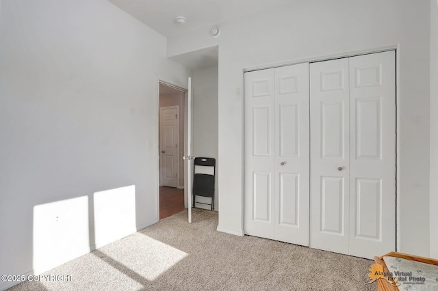 unfurnished bedroom with light carpet, a closet, and baseboards