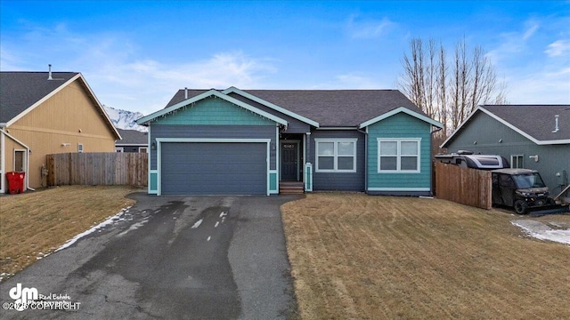 view of front facade with driveway, a front lawn, an attached garage, and fence