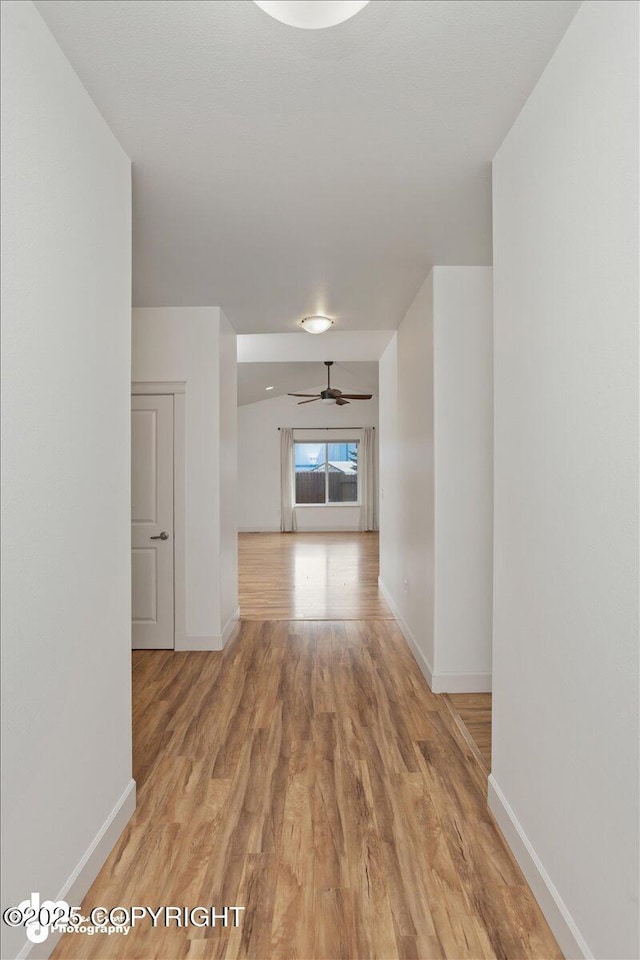 corridor with light wood-style flooring and baseboards