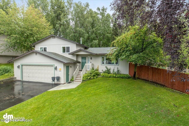 tri-level home with aphalt driveway, a garage, a front yard, and fence