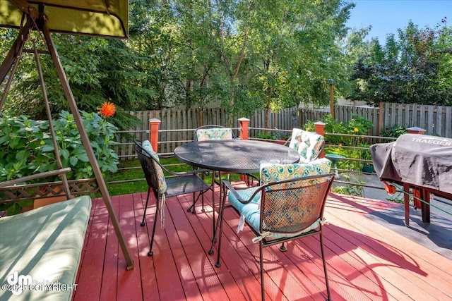 wooden deck with outdoor dining space, a fenced backyard, and grilling area