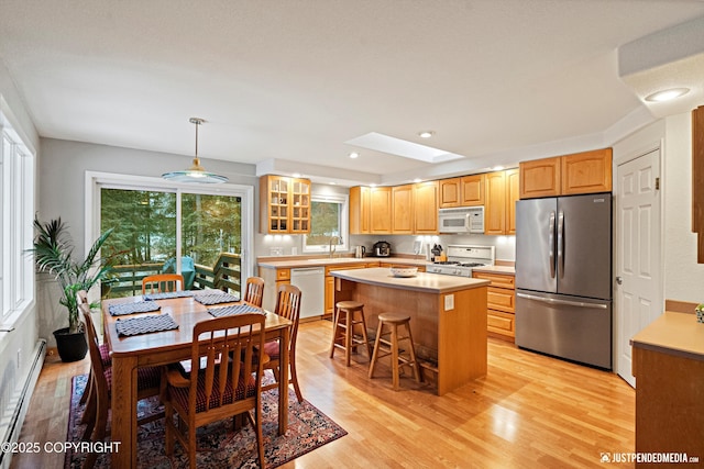 kitchen with a baseboard heating unit, stainless steel appliances, a skylight, light countertops, and light wood-type flooring