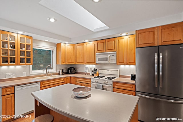 kitchen featuring recessed lighting, white appliances, a kitchen island, a sink, and glass insert cabinets