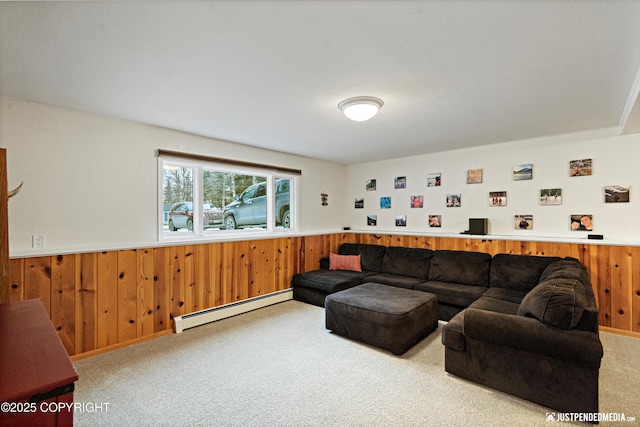 carpeted living room featuring wood walls, baseboard heating, and wainscoting