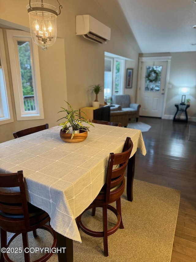 dining area with lofted ceiling, a wall mounted air conditioner, an inviting chandelier, and wood finished floors