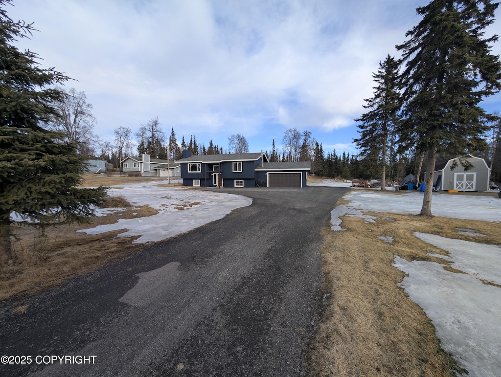 view of front of property with aphalt driveway and a storage shed