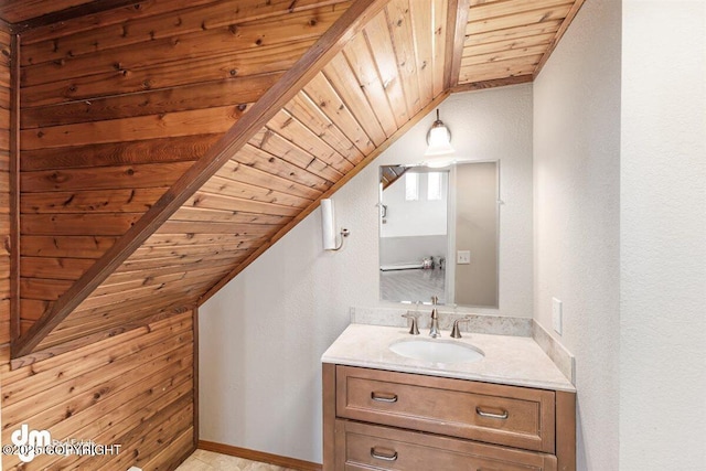 bathroom featuring vanity, lofted ceiling, a textured wall, baseboards, and wood ceiling