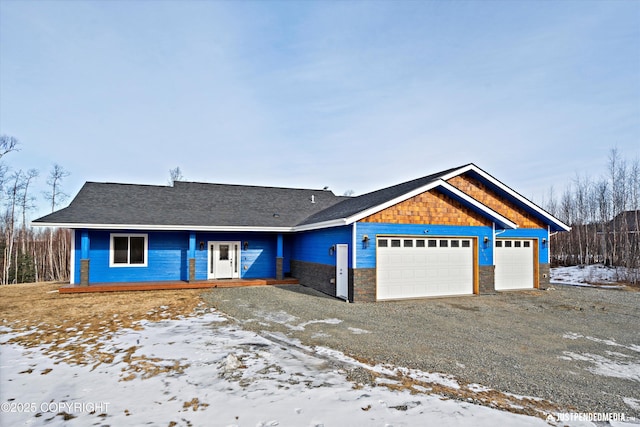 view of front of home featuring a garage, driveway, and stone siding