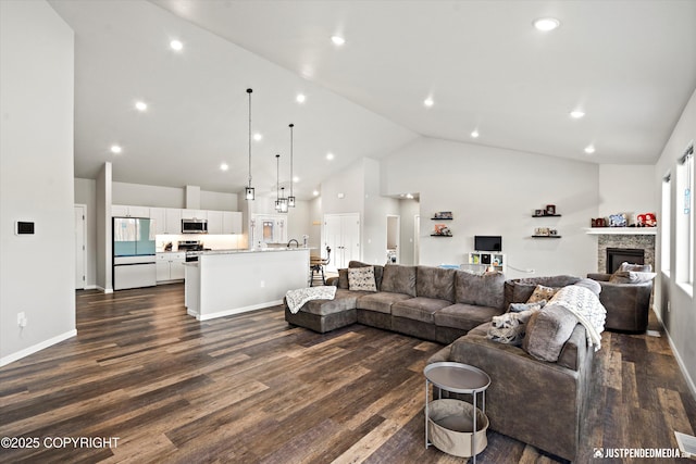 living area featuring high vaulted ceiling, a stone fireplace, recessed lighting, dark wood-style flooring, and baseboards