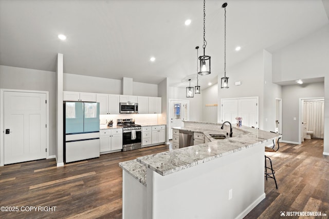 kitchen with dark wood-style floors, backsplash, appliances with stainless steel finishes, a sink, and a large island with sink