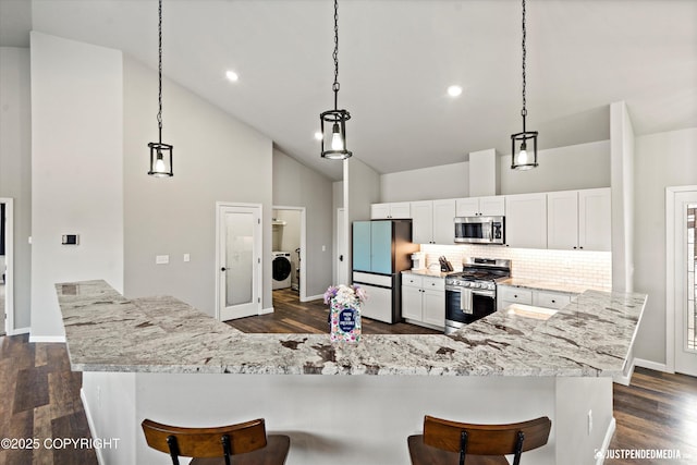 kitchen featuring tasteful backsplash, white cabinets, dark wood-type flooring, stainless steel appliances, and high vaulted ceiling