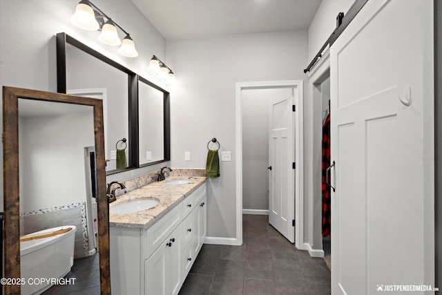 bathroom featuring tile patterned floors, a freestanding tub, a sink, and double vanity